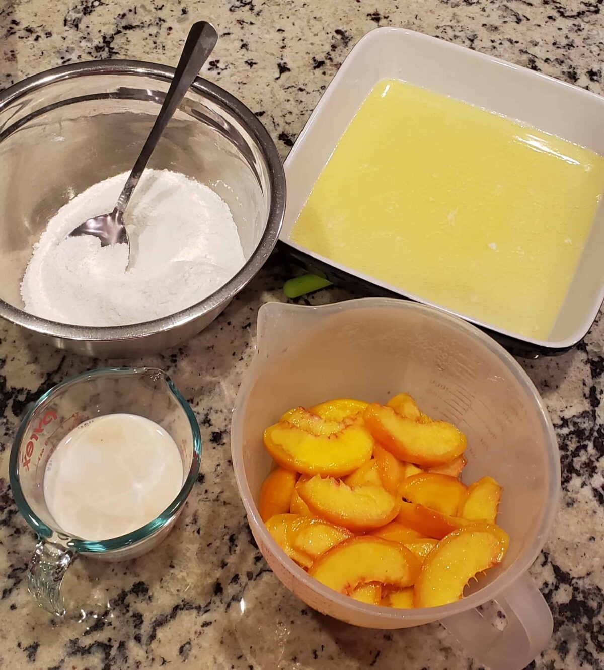 nectarines in a measuring cup, bowl of sugar, square dish with melted butter, 