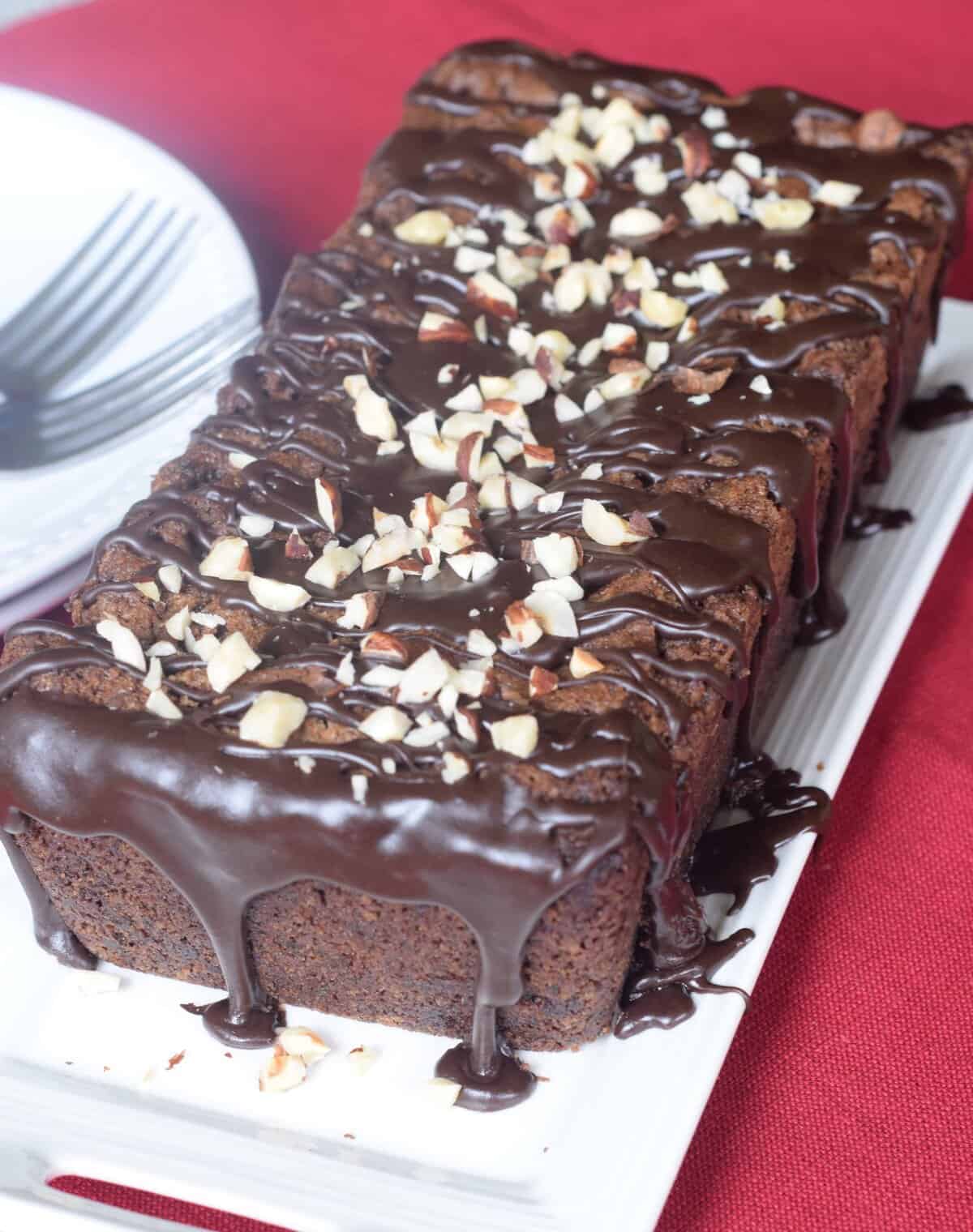 Chocolate loaf of bread with ganache drizzled over with chopped hazelnuts sprinkled