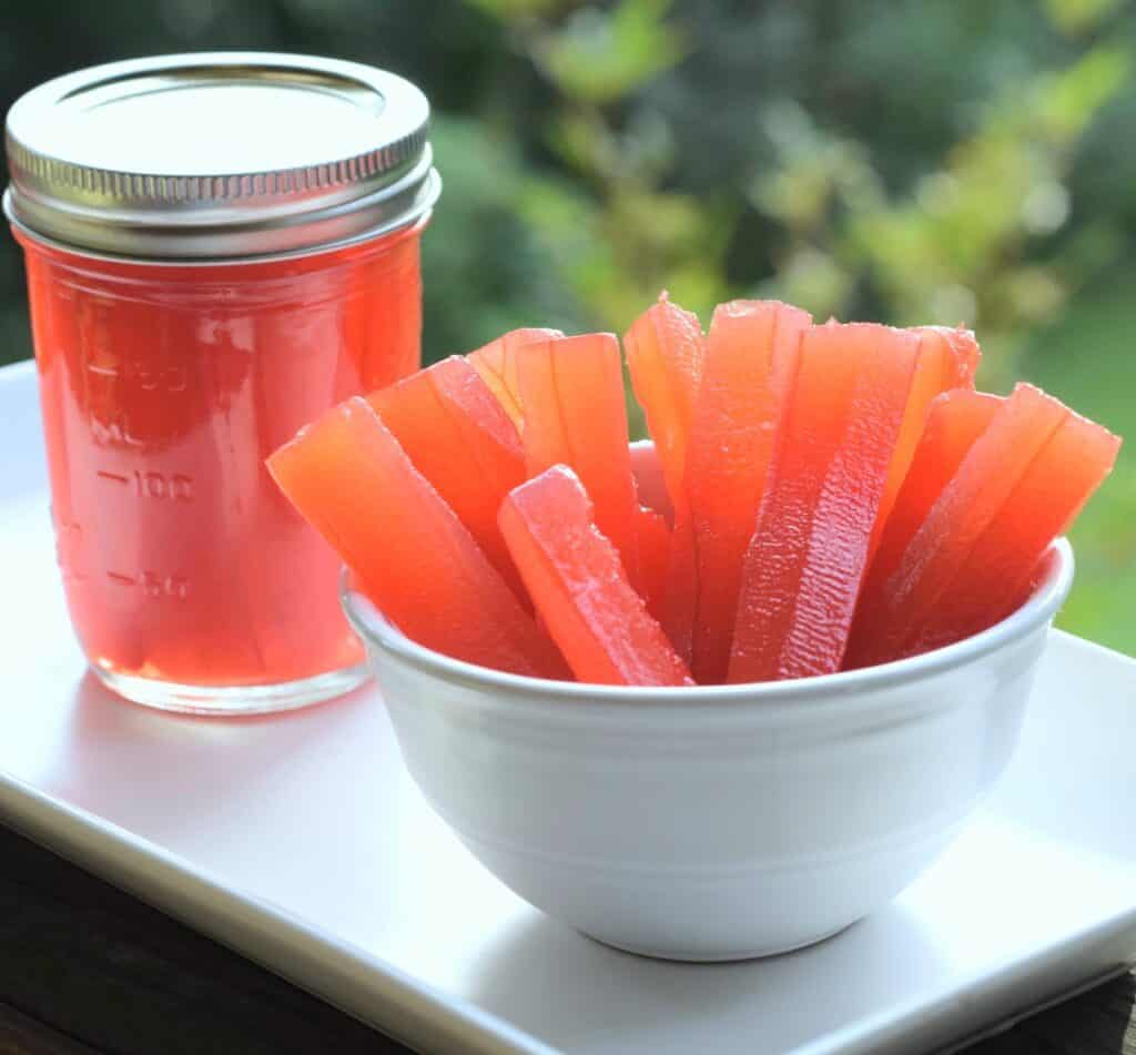 Jar of red pickles next to bowl of red pickle sticks