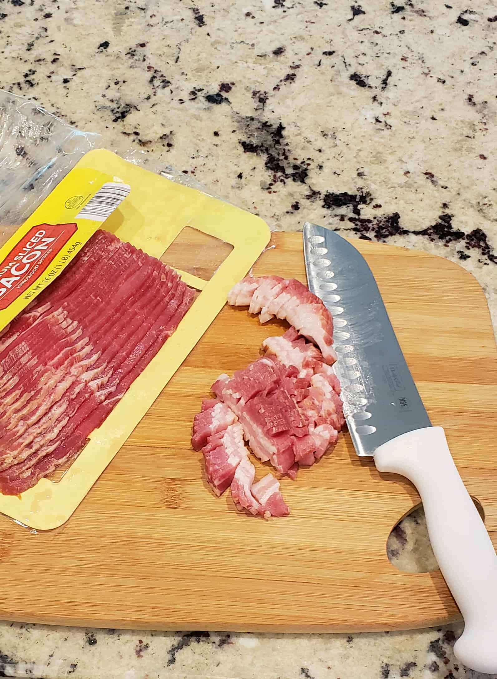  slices of bacon cut up on a wooden cutting board