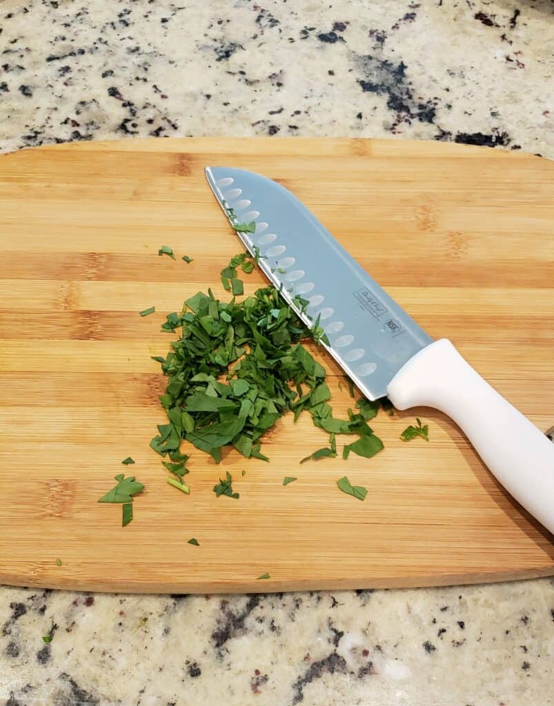 Chop fresh parsley using a chefs knife on a cutting board. It is so much easier than trying to use a paring knife.