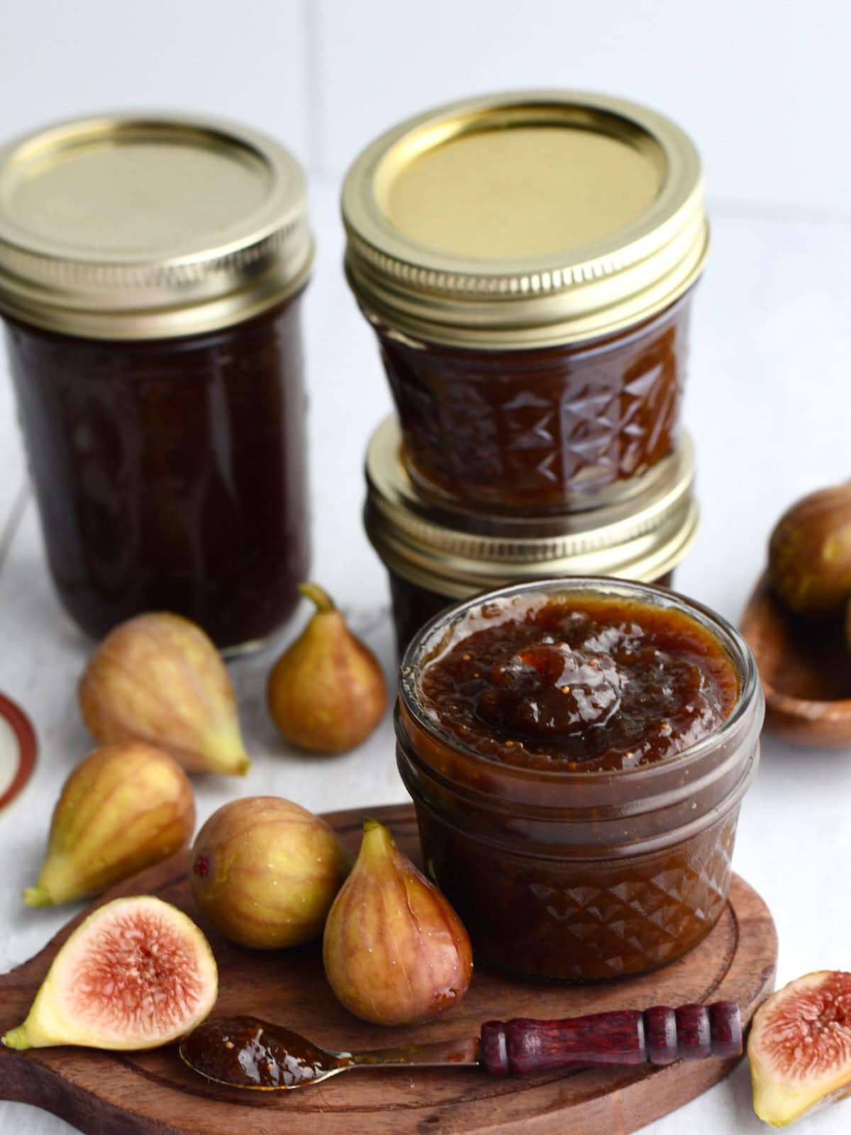 Jars of fresh fig jam with fresh figs cut in half.
