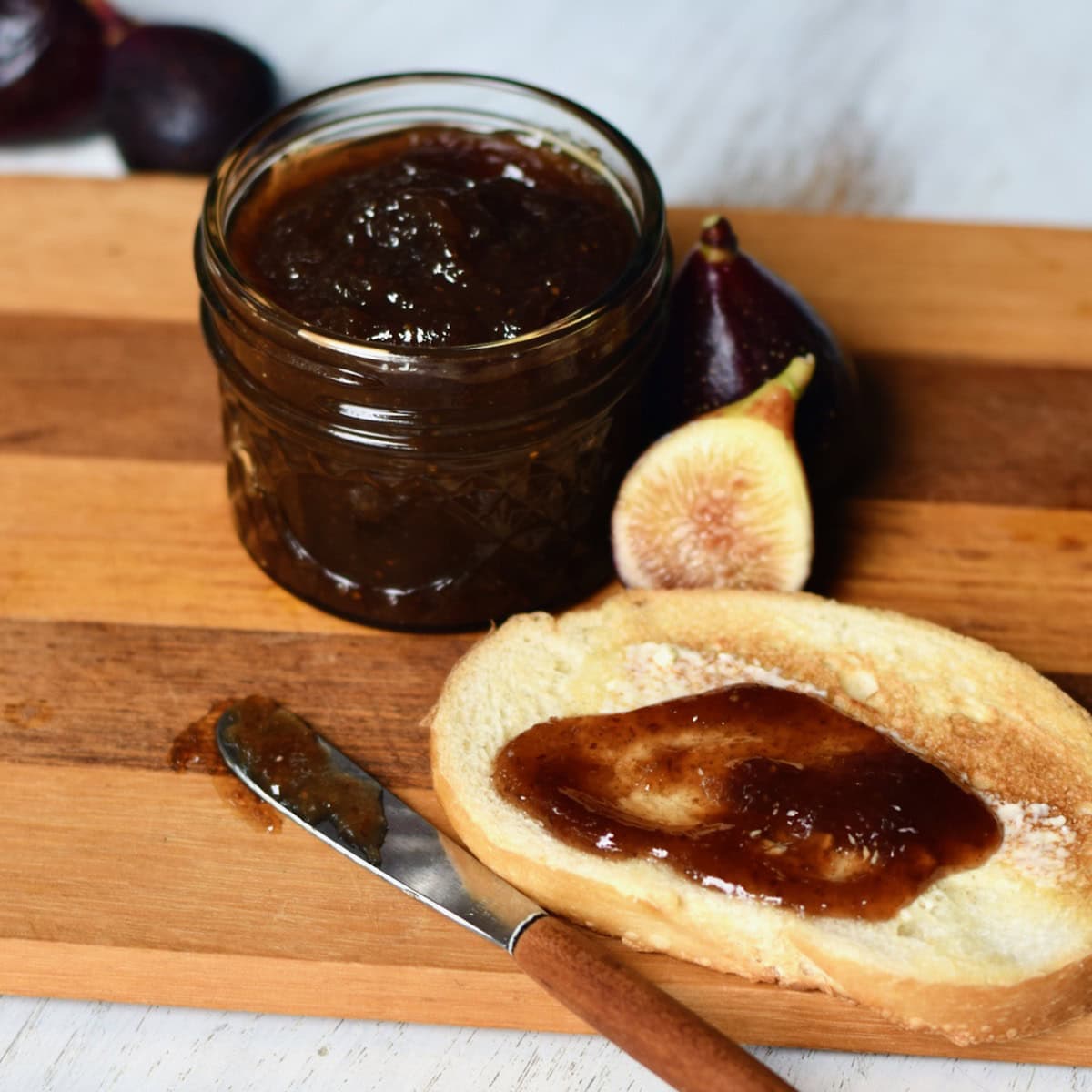 Spiced fig jam on toast next to a jar of opened fig jam.
