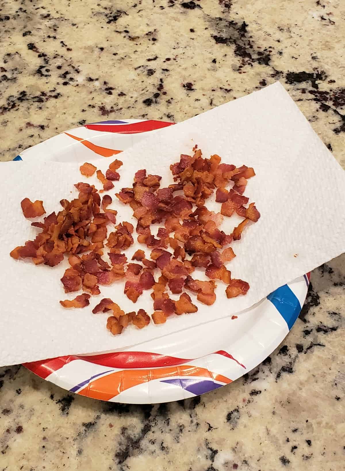 Bacon bits draining on paper towels on a paper plate.