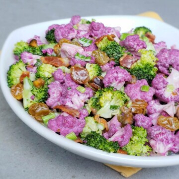 White rimmed plate of purple cauliflower and broccoli salad