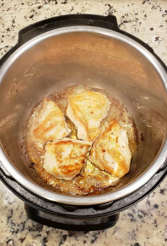 Four chicken breast halves searing in the Instant Pot.