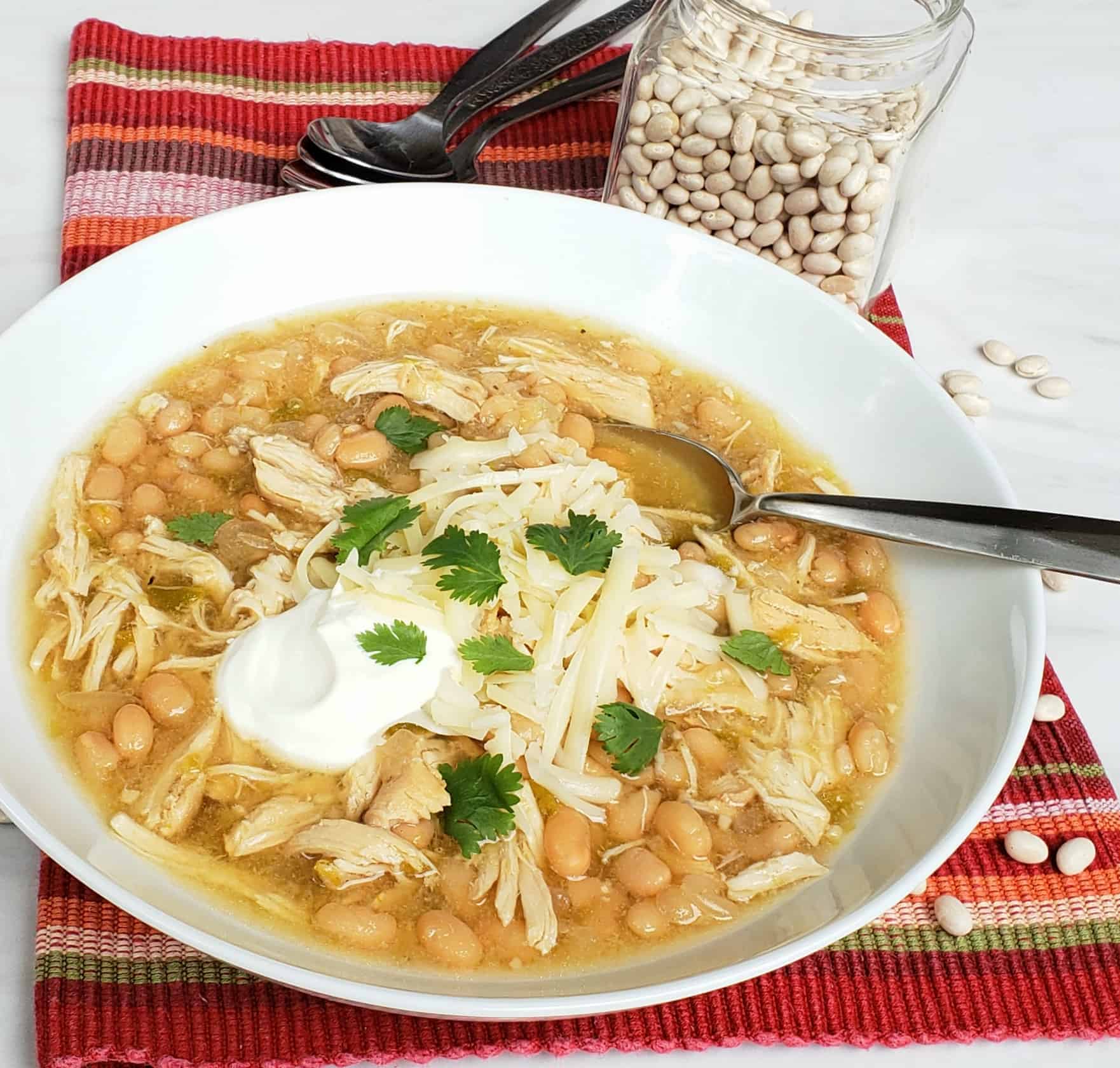 white bean chicken chili in white bowl on red cloth