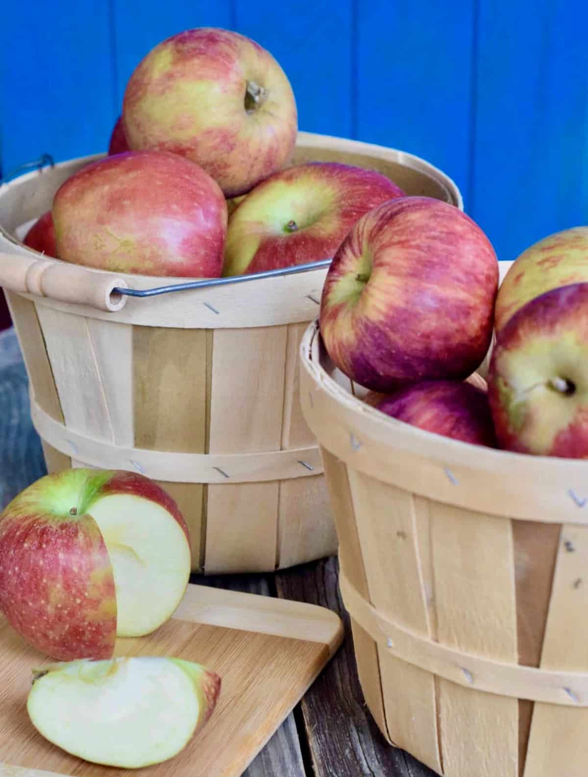 Two wooden baskets of apples with one apple wedge cut out.