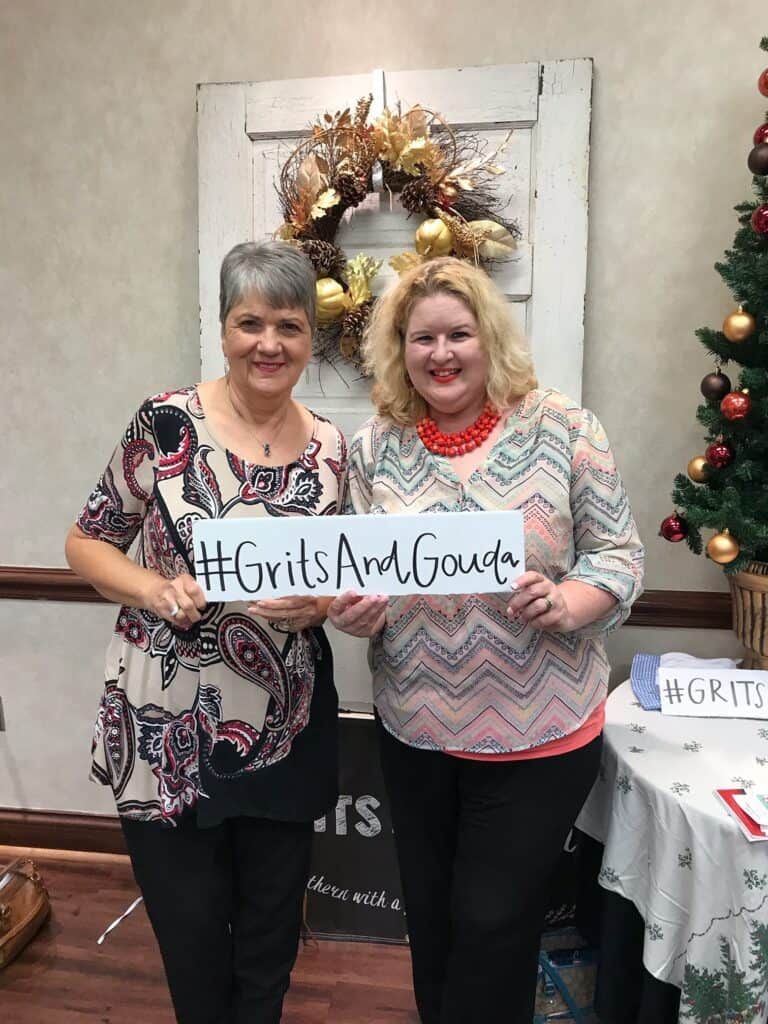 Guests holding up Grits and Gouda selfie signs at the Holiday Cooking Show