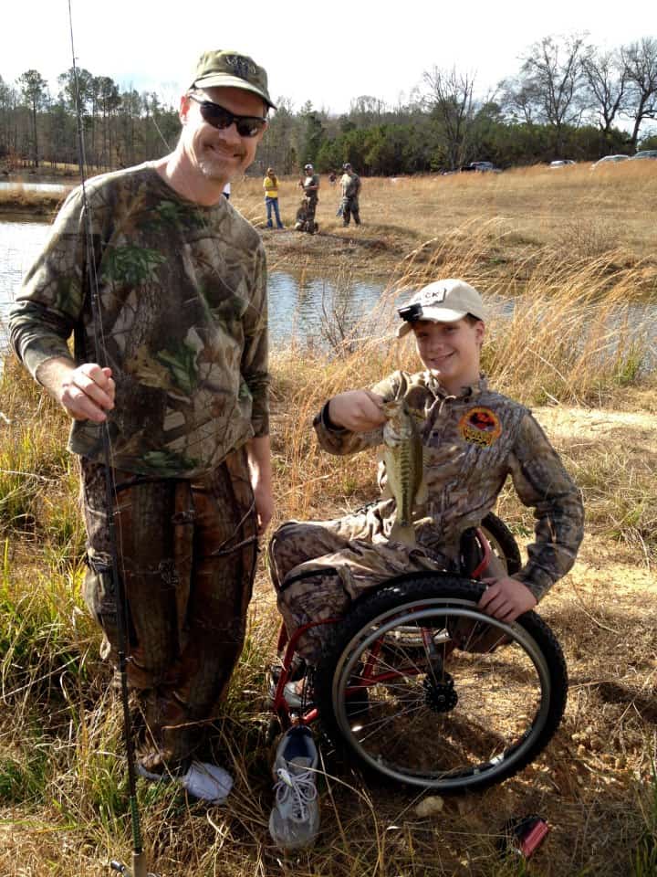 Scott and Grayson Phillips holding up an albino fish boy in wheelchair fishing