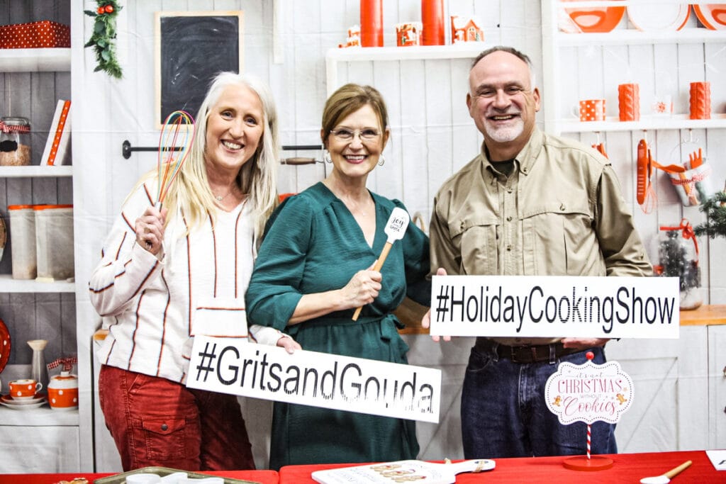 Man and woman holding signs with woman in green dress in middle.