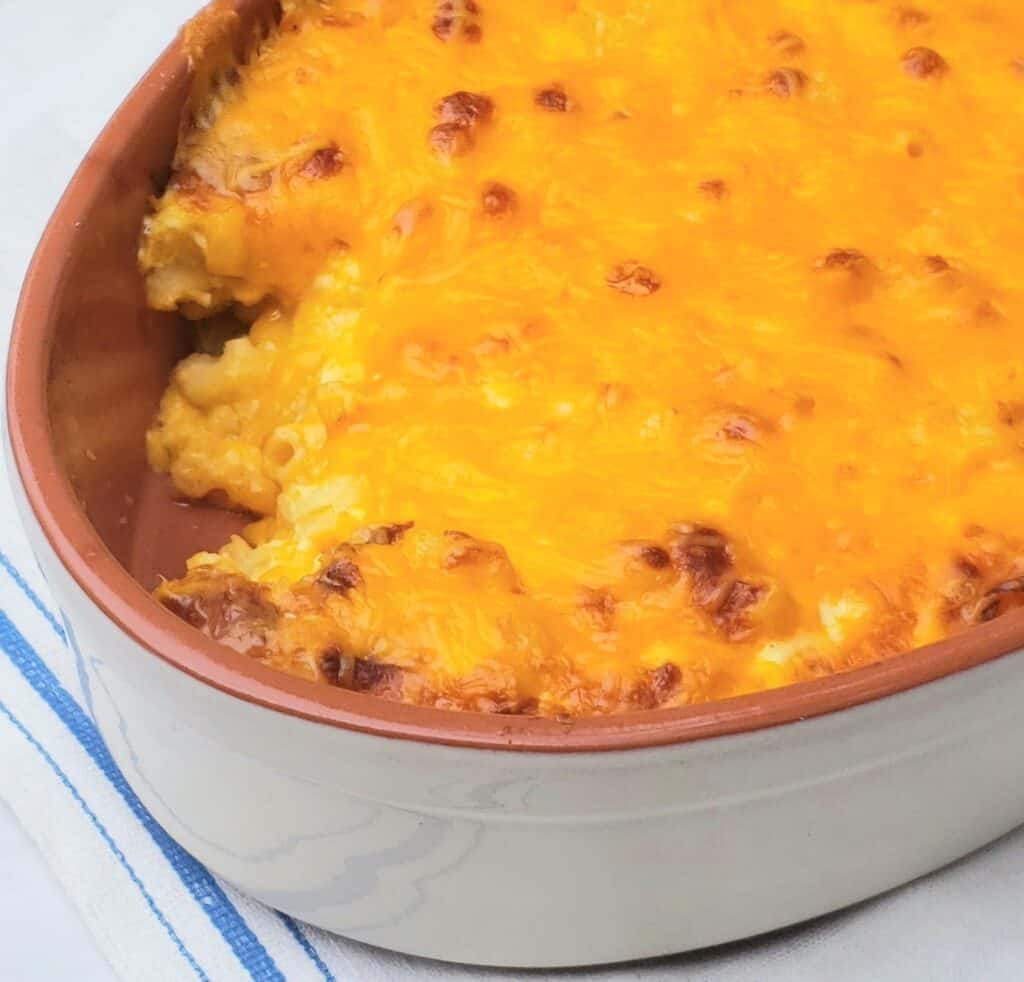 baked macaroni and cheese in tan baking dish with serving scooped out.