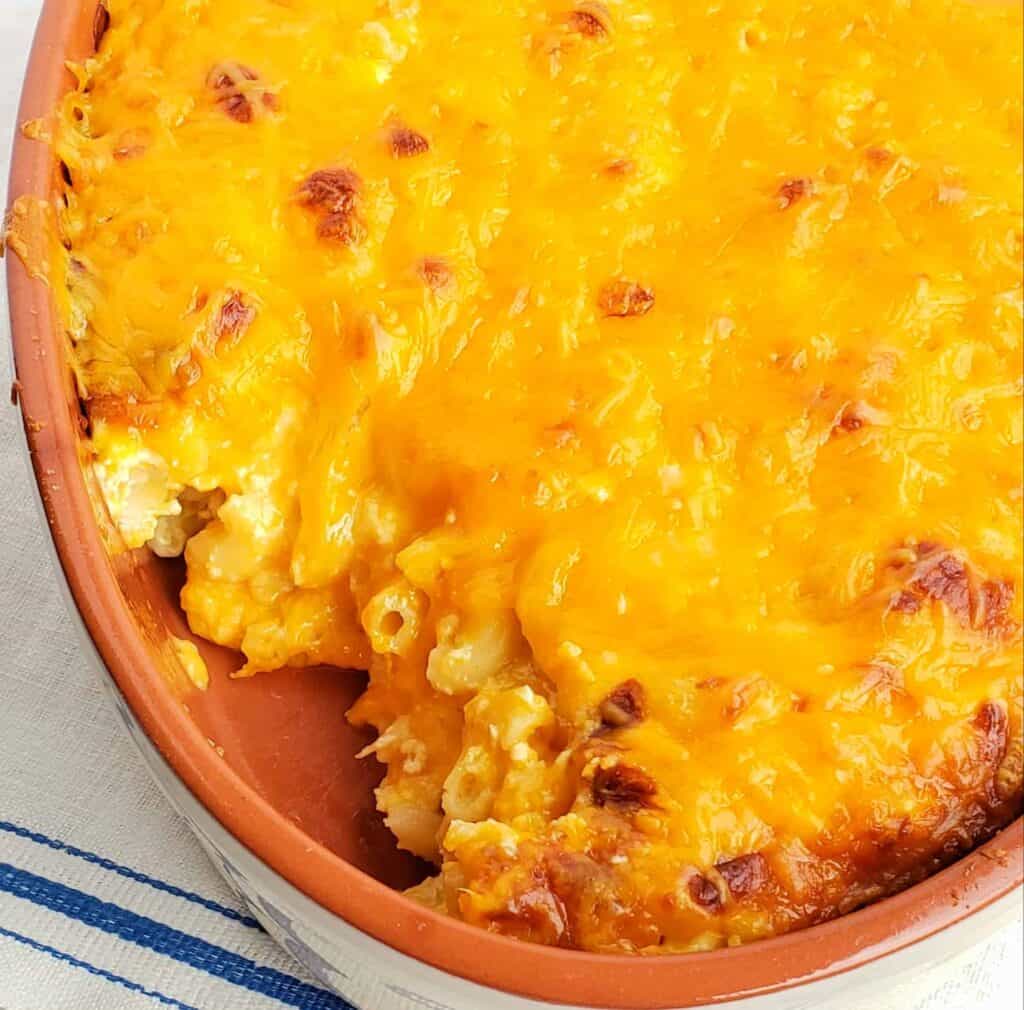 Macaroni and cheese in tan dish with scoop out
