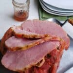 bone in ham with slices cut on the ham. jar of jelly