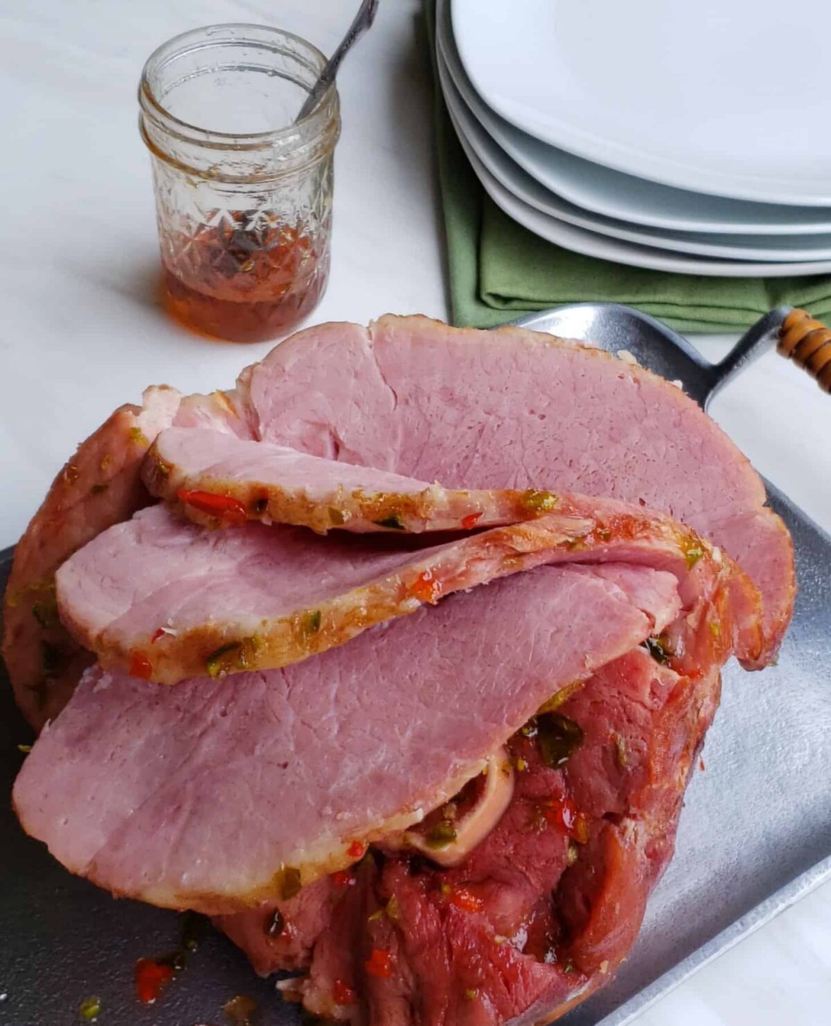 bone in ham with slices cut on the ham. jar of jelly