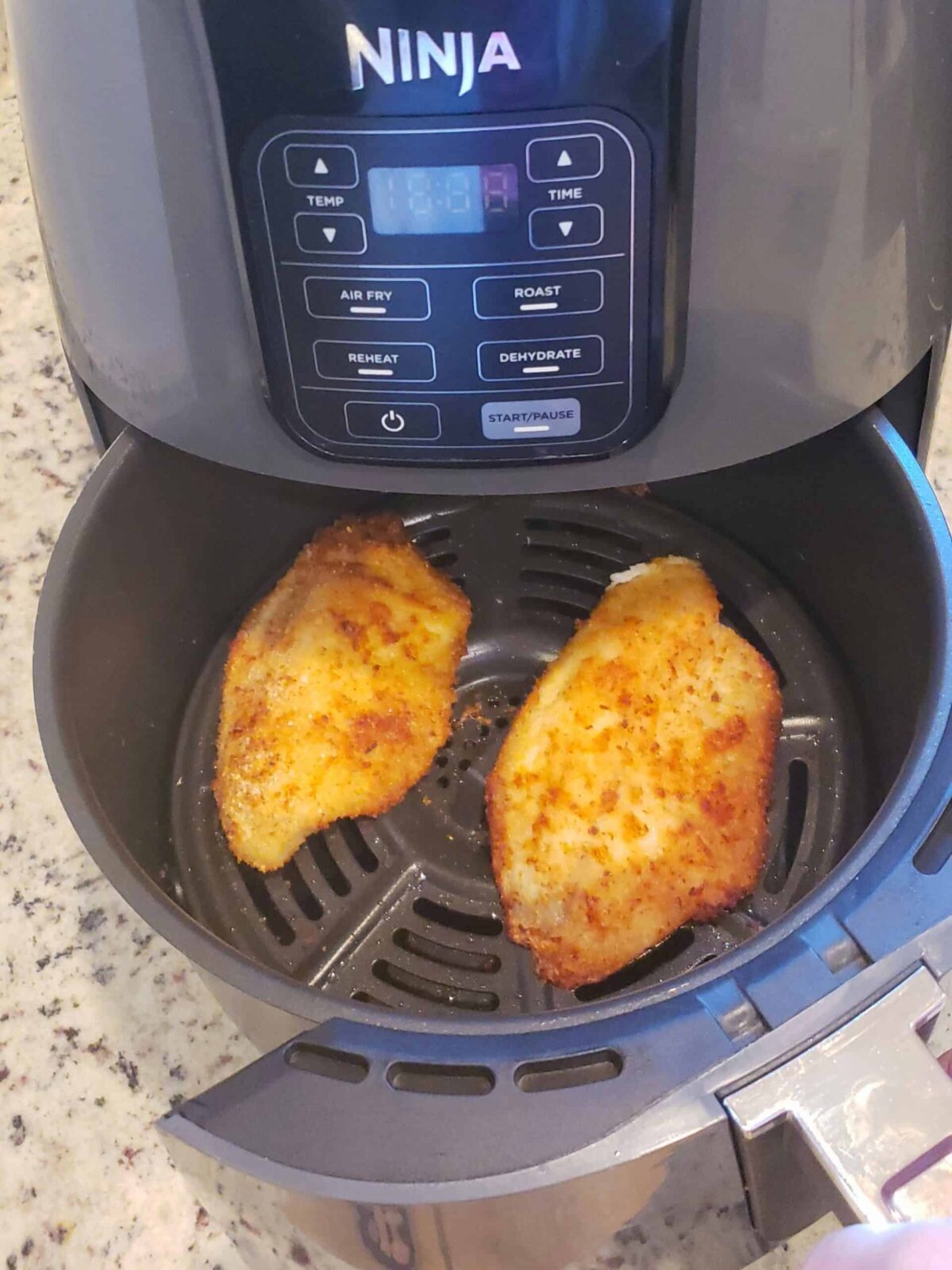 2 air fried tilapia fillets in air fryer basket