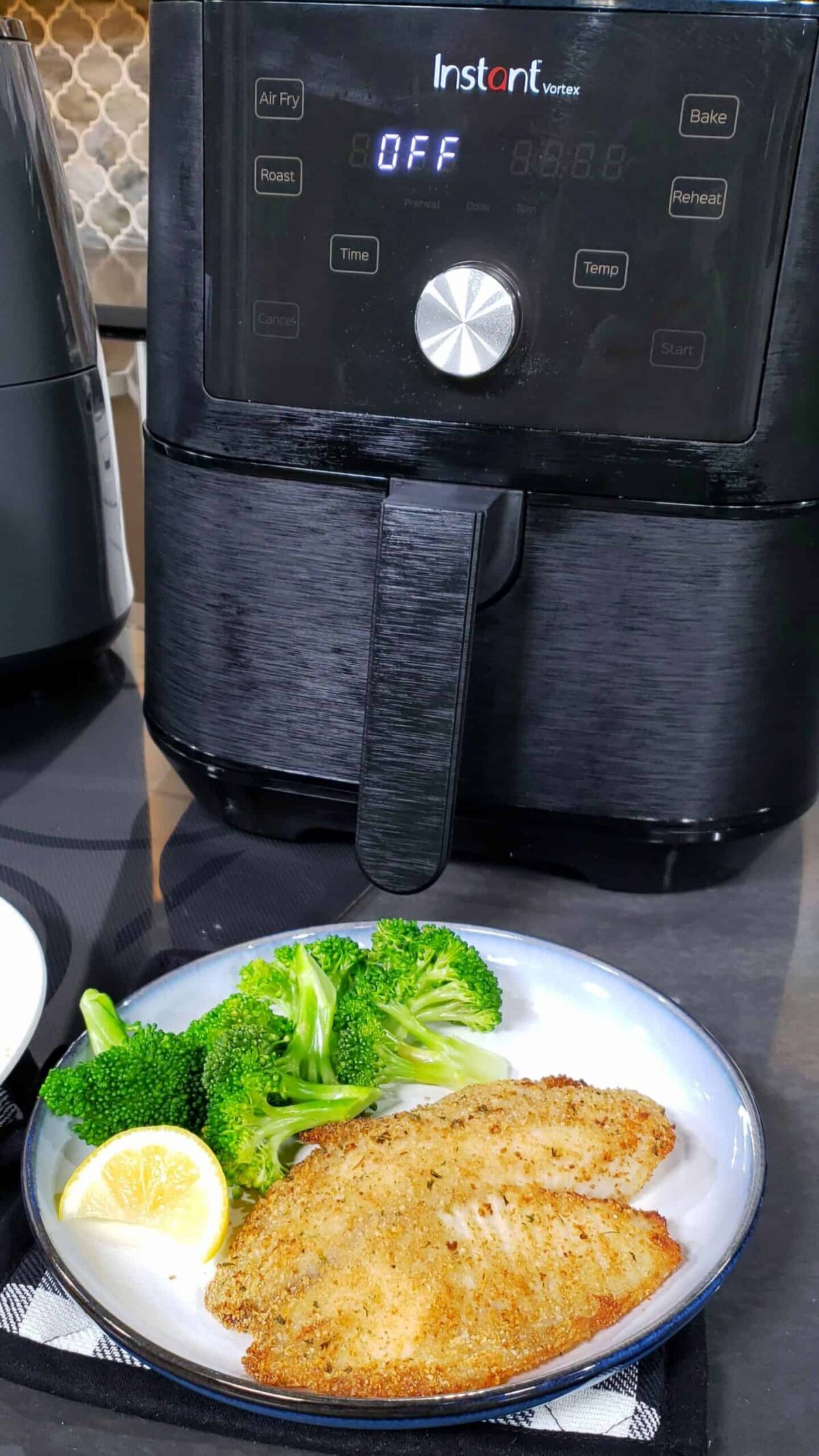 breaded tilapia on blue and white plate with broccoli and lemon with air fryer