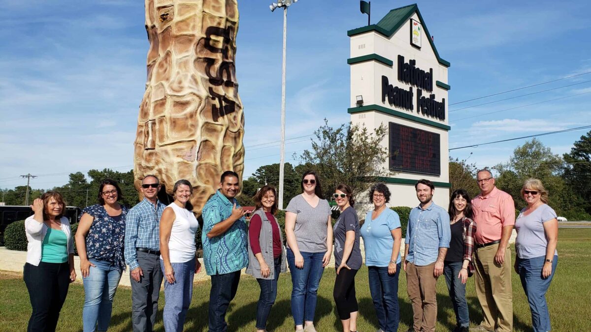 Group of adults in front of Peanut Festival sign