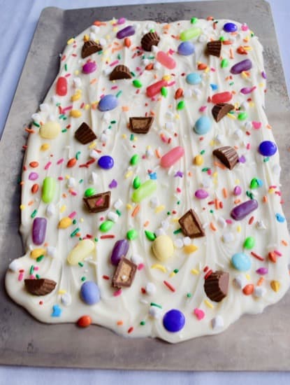 slab of white chocolate bark with candy pressed into them on sheet pan