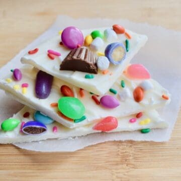 Three stacked pieces of white chocolate bark with Easter candy pressed into them placed on parchment paper