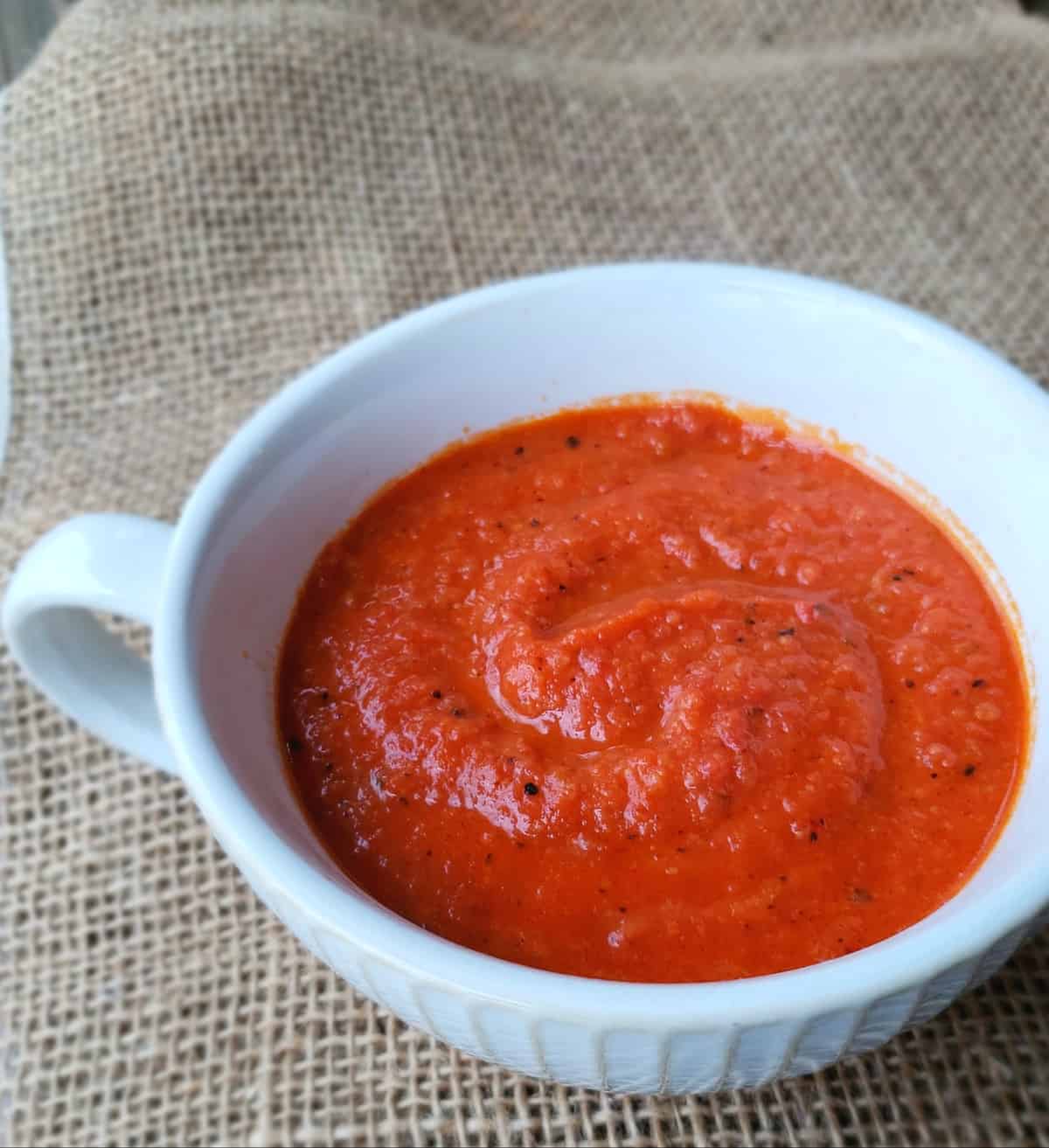 Close up white bowl of tomato soup on burlap