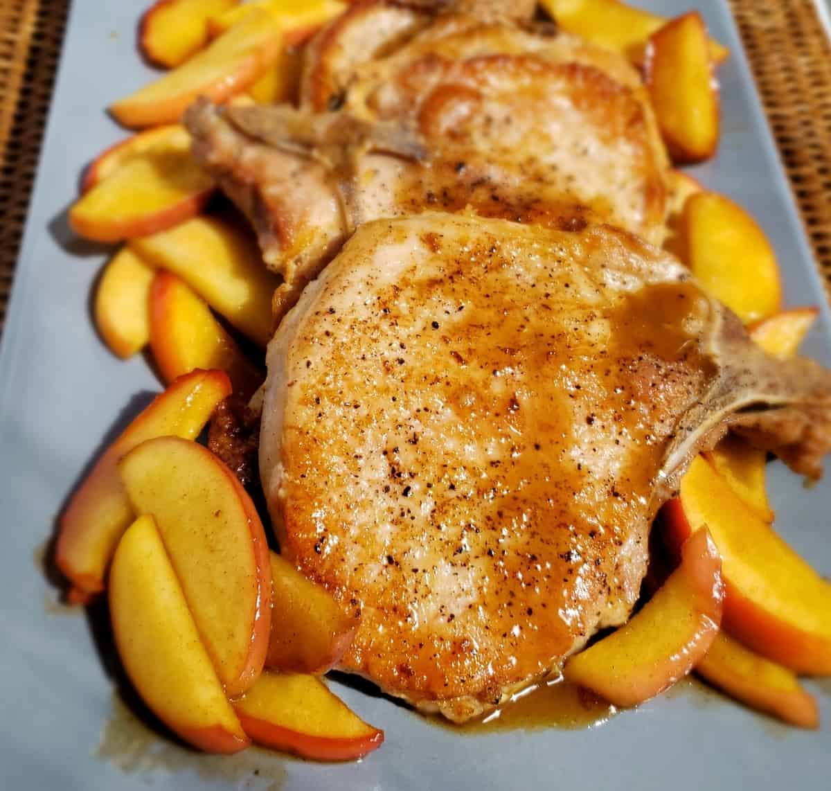 Seared bone-in pork chops with cinnamon apples on either side of them.