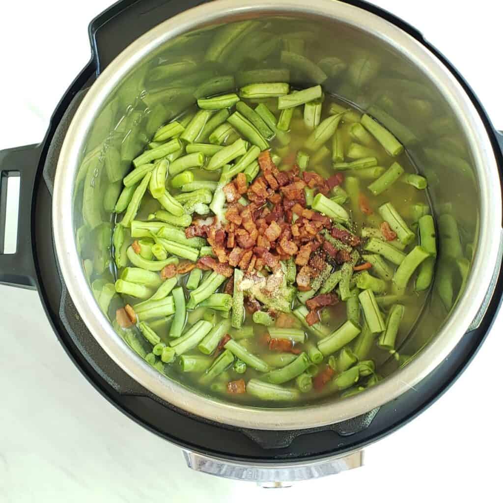 Raw green beans with bacon and chicken broth in the instant pot. 