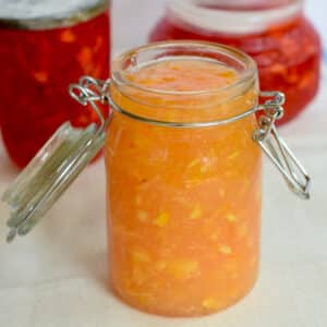 Peach Freezer Jam in old fashioned glass jar with wire clamp. Strawberry jam in background.