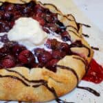 cherry galette with chocolate drizzled over and melting ice cream in middle