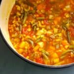 Half of an enamel-coated pot full of vegetable soup