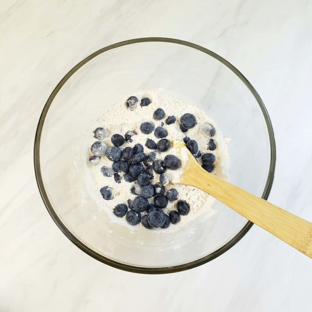 Stirring blueberries with flour in glass bowl