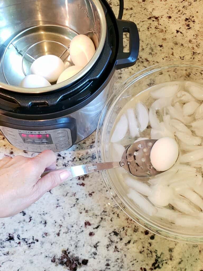 Spooning eggs from Instant Pot into bowl of ice water
