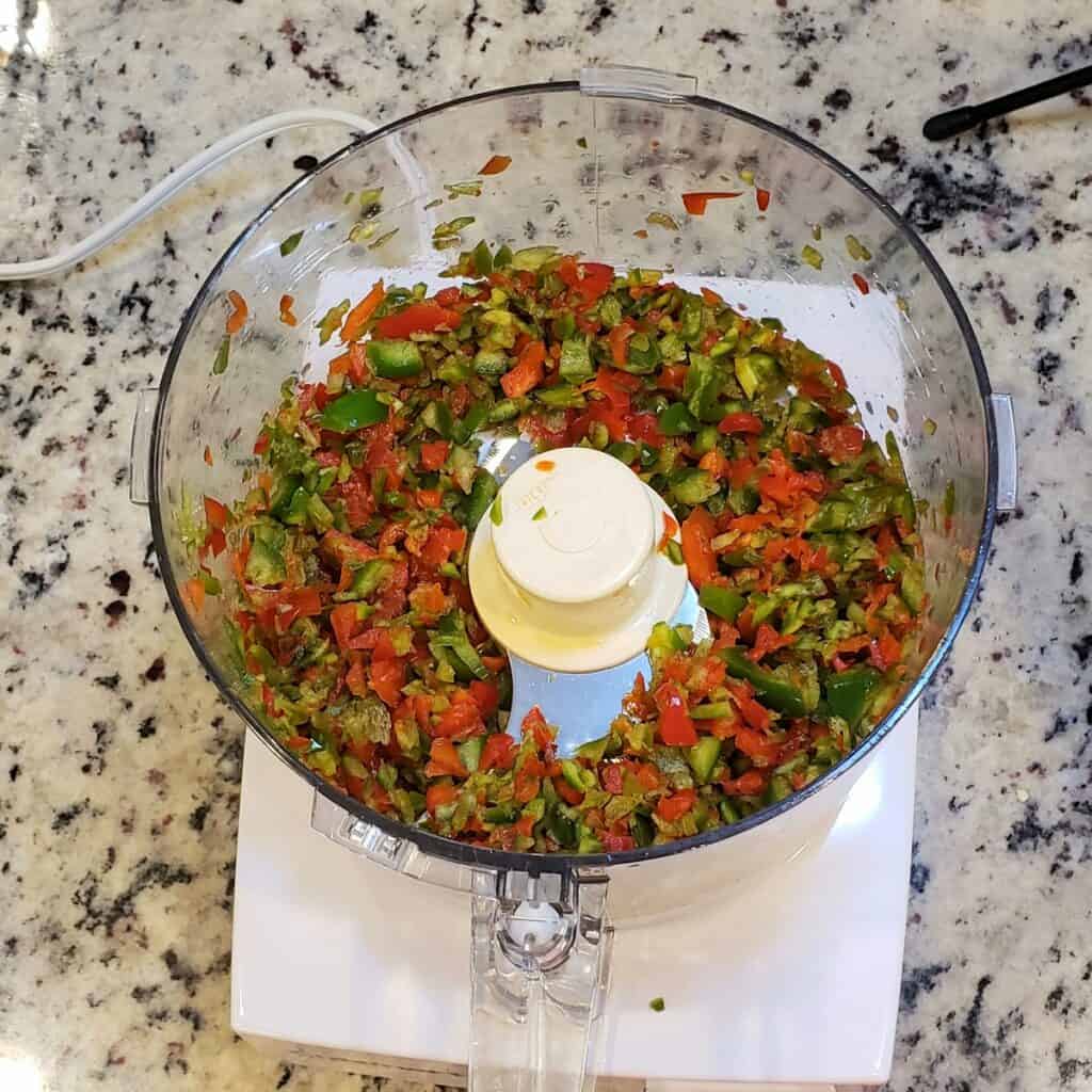 Minced jalapeno and red pepper minced in a food processor; top view