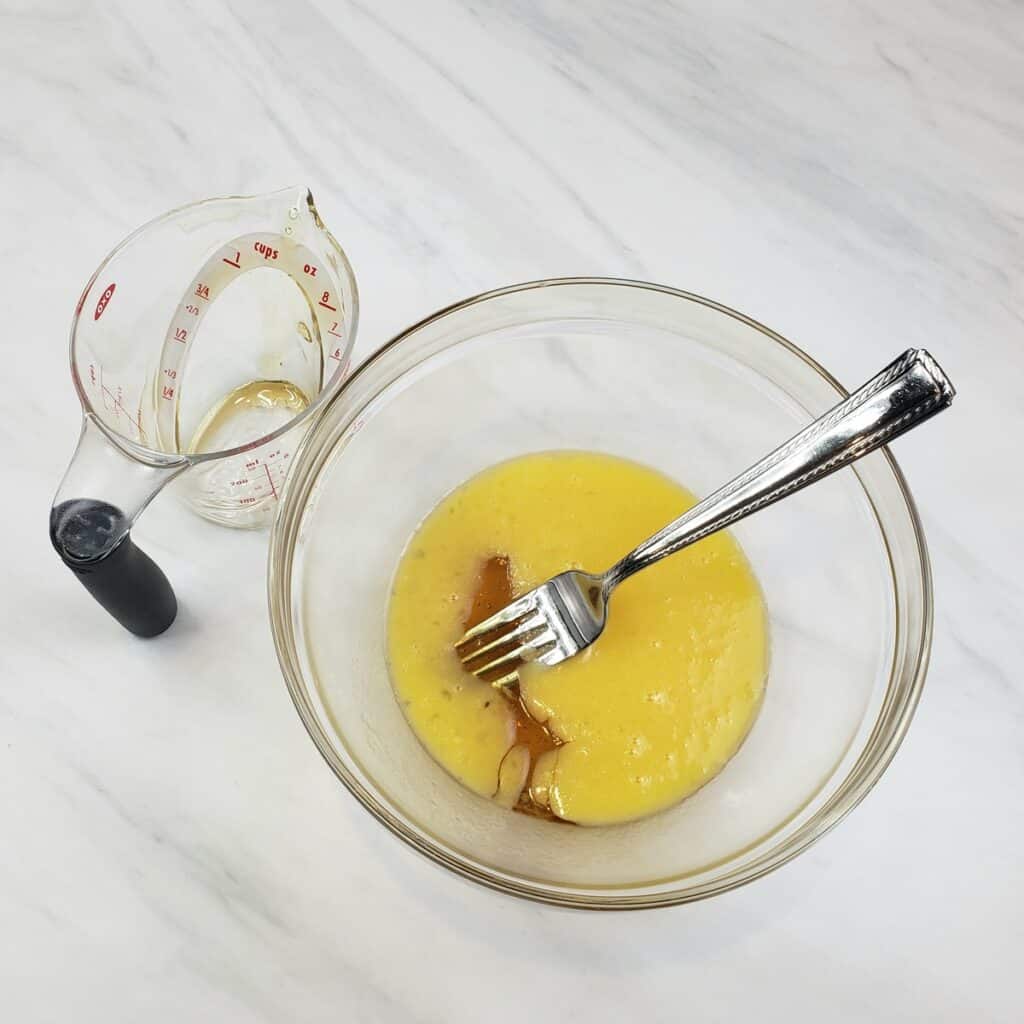 Melted butter and honey in a glass bowl with a fork