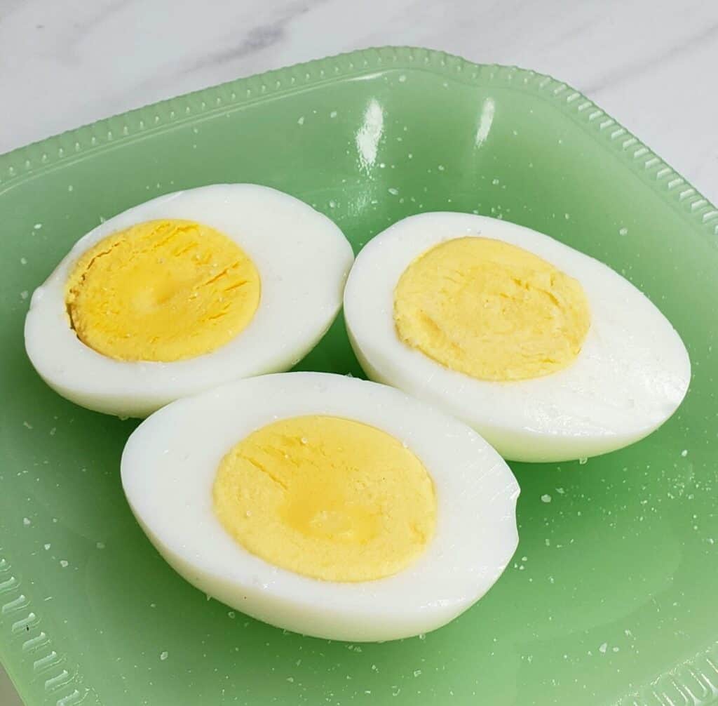 hard cooked eggs cut in half on a green plate