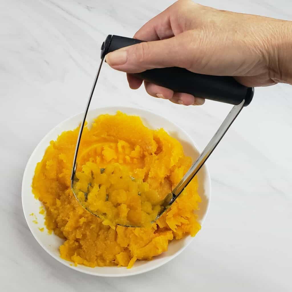 Potato masher mashing pumpkin puree