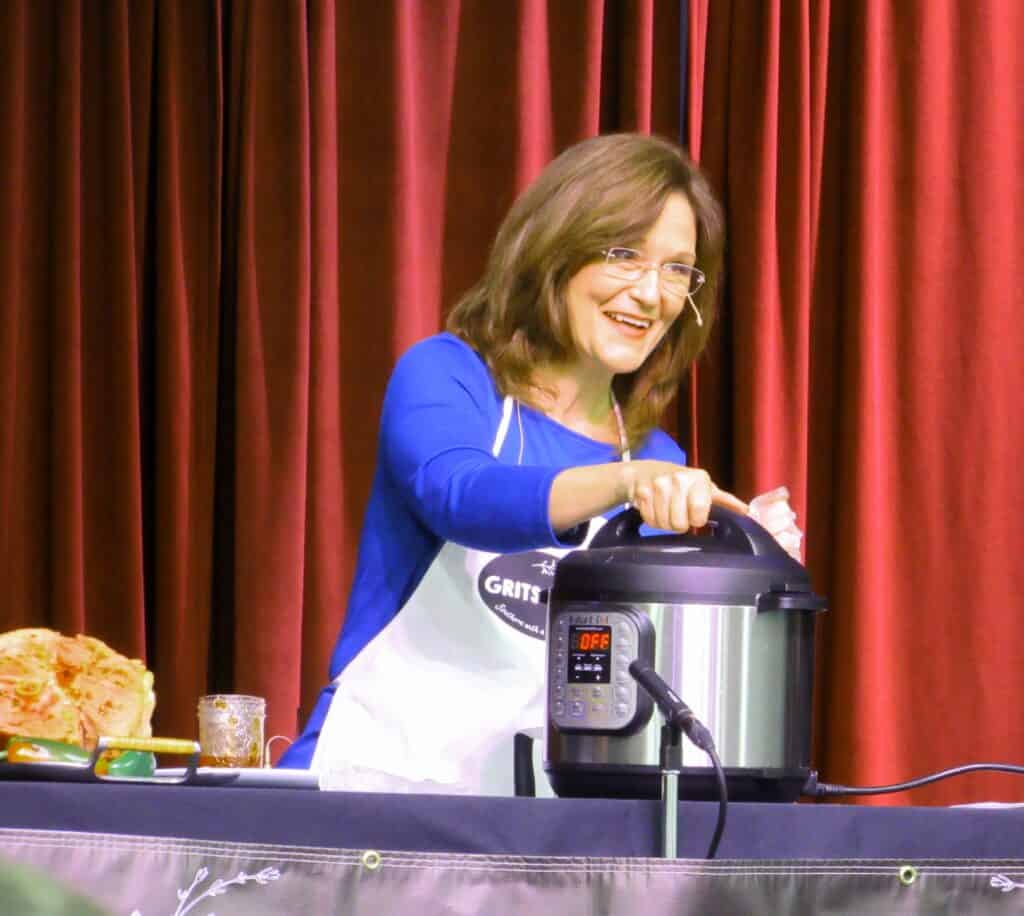 woman behind Instant Pot with red curtains behind her