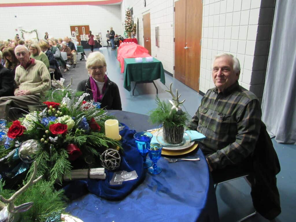 man and woman sitting at round table decorated for Christmas