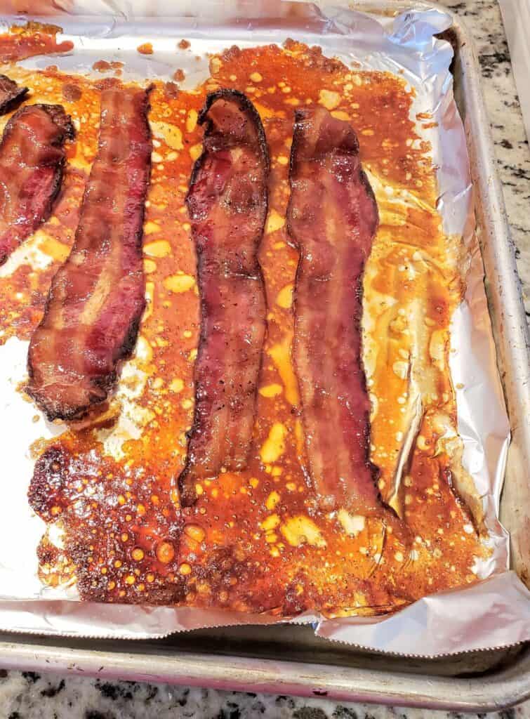 Slices of bacon candied on a foil lined sheet pan