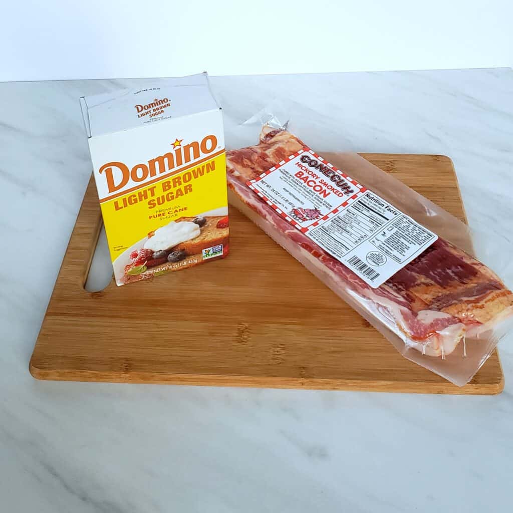 A package of bacon and a box of brown sugar on a wooden cutting board