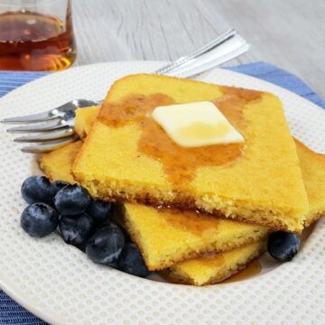 Stack of square pancakes with butter and blueberries on white plate