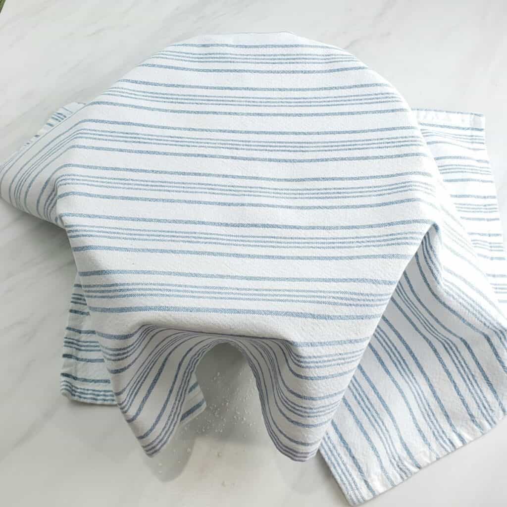 Blue and white towel draped over a bowl on marble surface