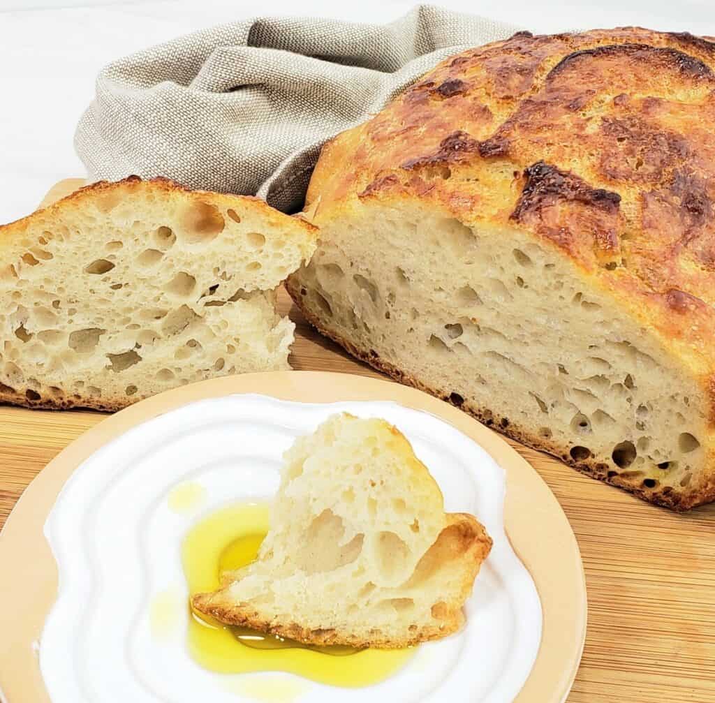 Slice out of artisan round loaf bread. Piece of bread sitting in oil in a plate