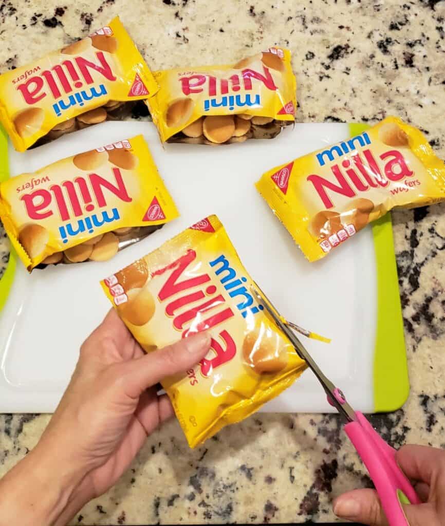 Cutting vanilla wafer cookie packages open with scissors