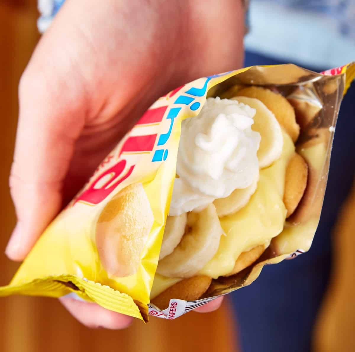 A hand holding banana pudding in a cookie bag