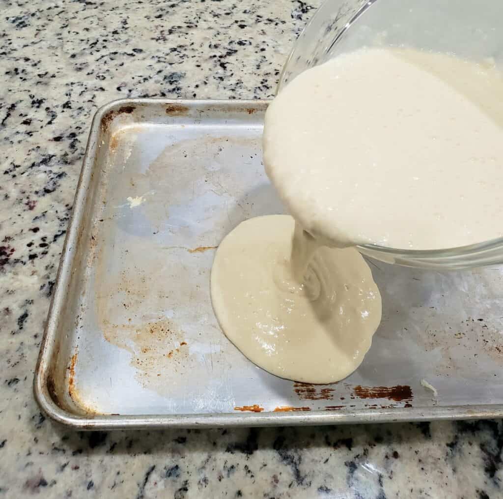 Pancake batter being poured onto a sheet pan