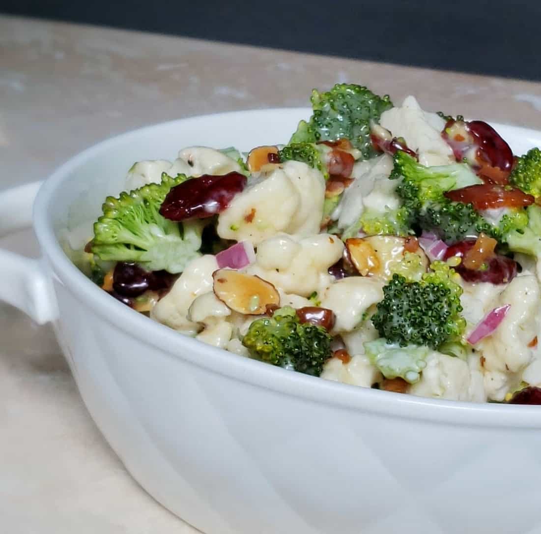 White bowl of broccoli cauliflower salad