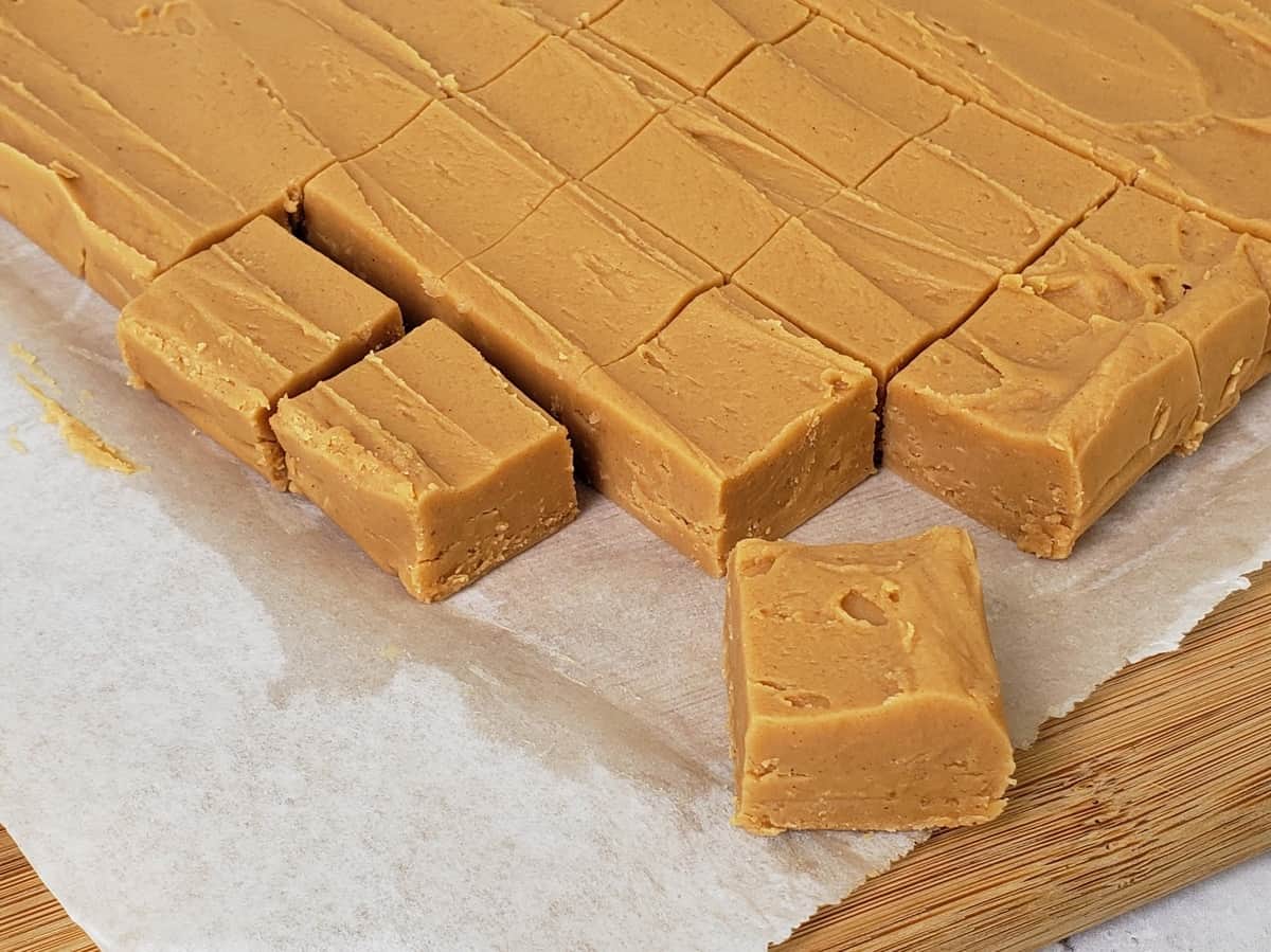 2 Ingredient Peanut Butter Fudge cut into squares on wooden cutting board.