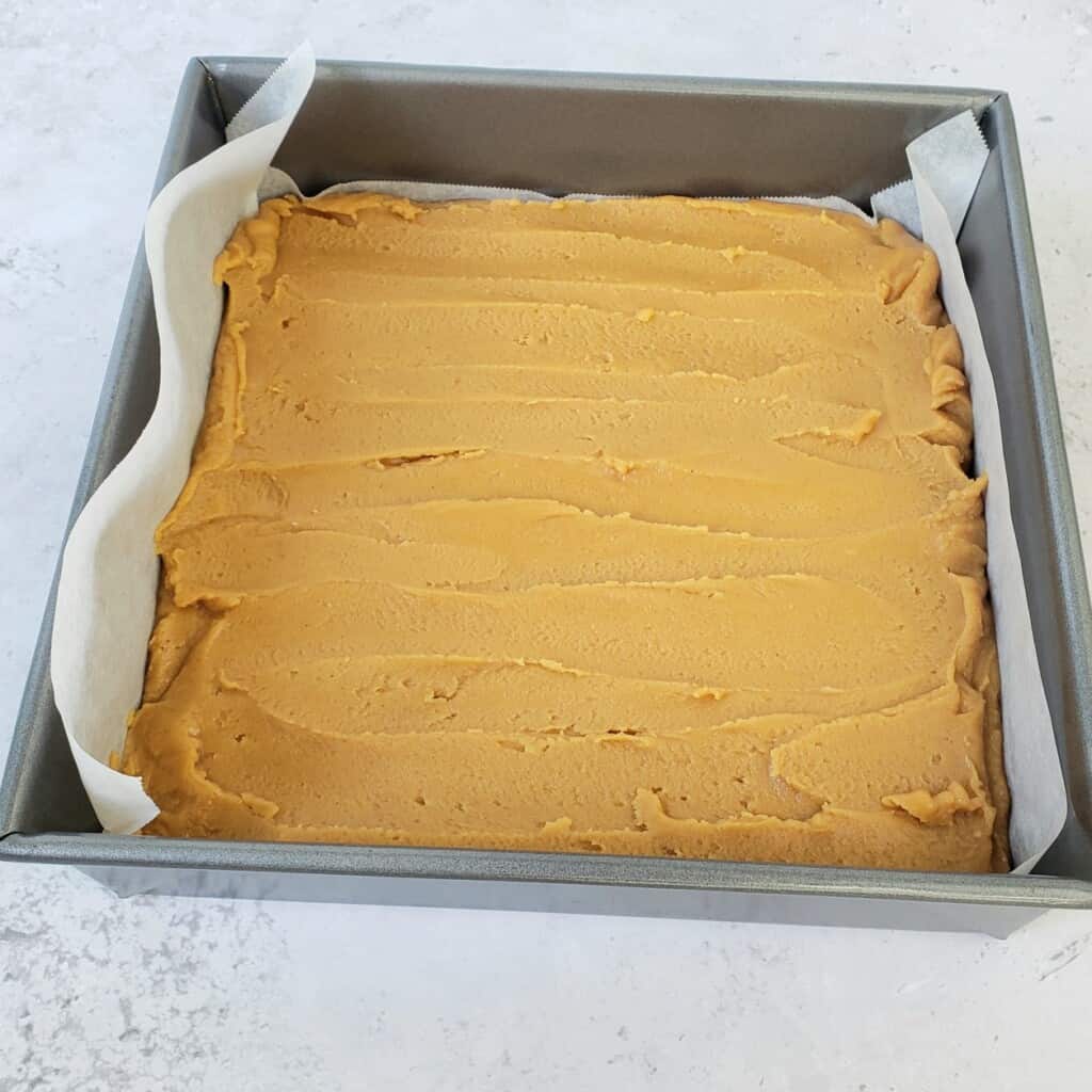 Peanut Butter fudge spread into a parchment paper-lined pan.