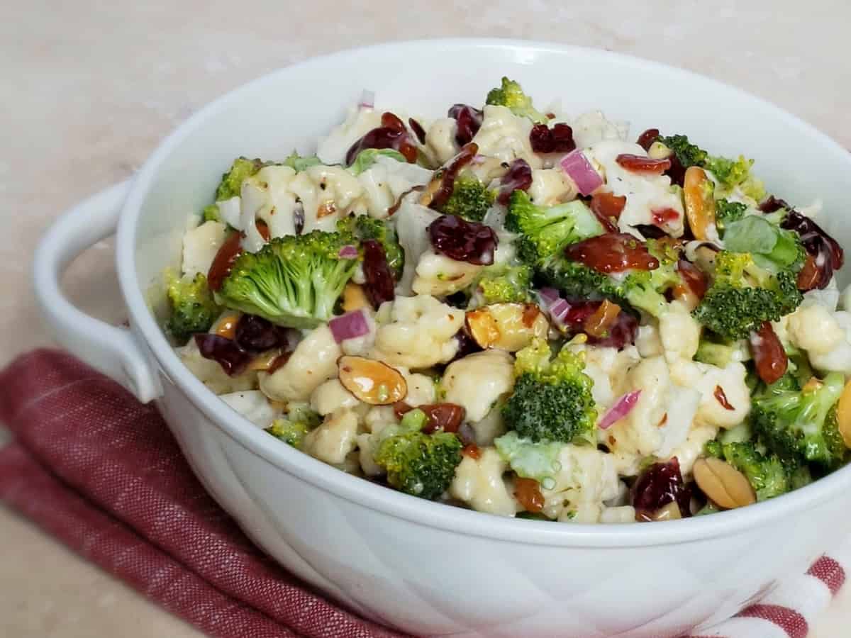 White bowl on pink cloth full of broccoli cauliflower mixture